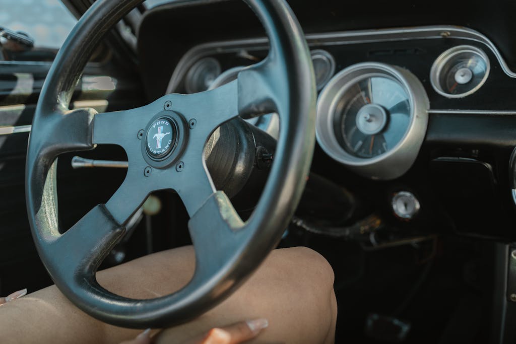 Imagen actual: Close-up of a vintage Ford Mustang steering wheel and dashboard showcasing retro car design.