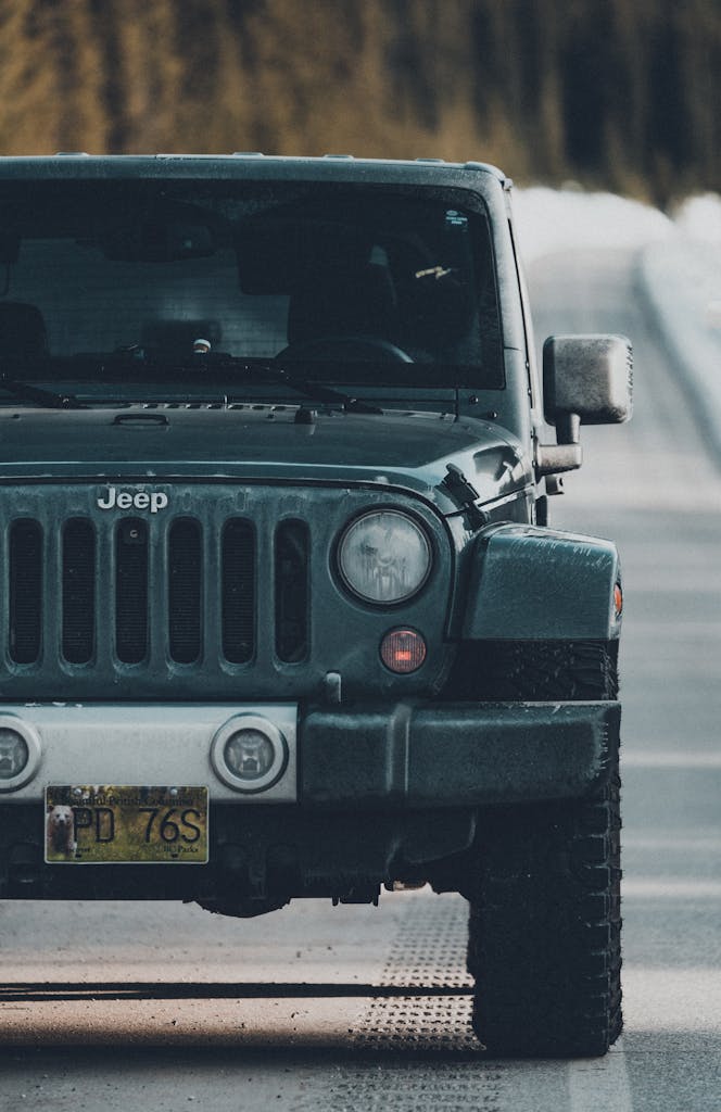 Imagen actual: A rugged Jeep Wrangler travels down a dusty road, surrounded by nature.