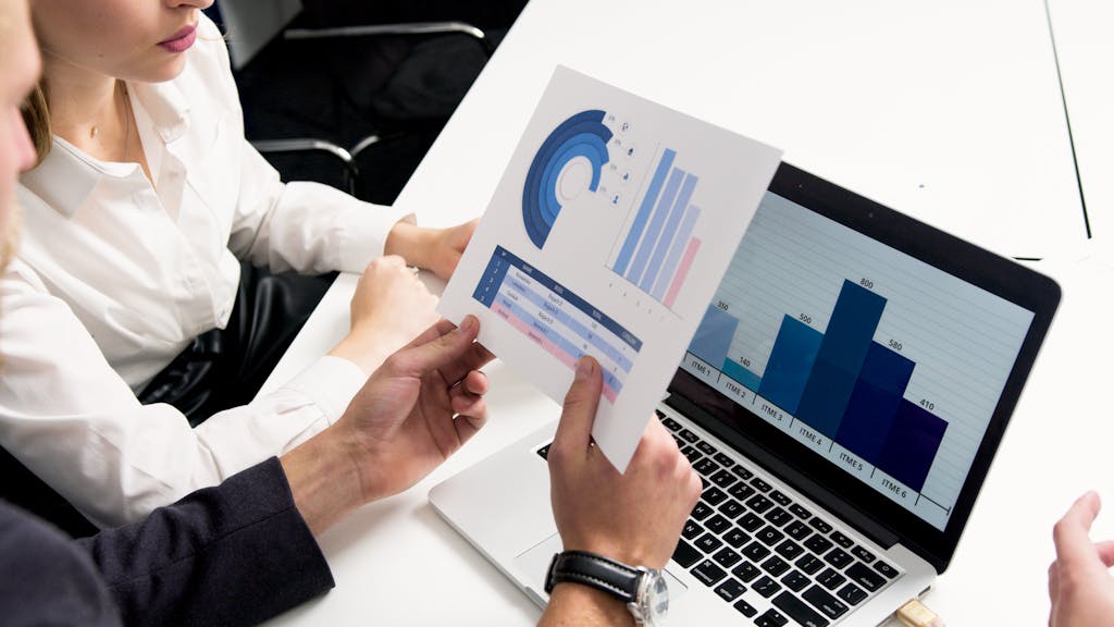 Imagen actual: Business professionals discussing data charts and graphs in a modern office setting.
