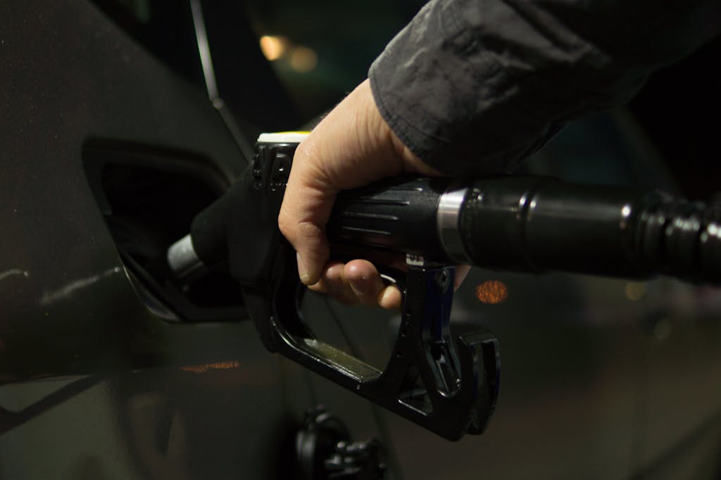 Imagen actual: Close-up of a person refueling a car at a gas pump during night.