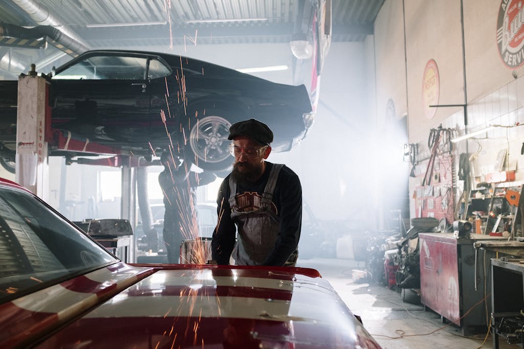 Imagen actual: Mechanic skillfully repairs a car in a bustling automotive workshop with sparks flying.