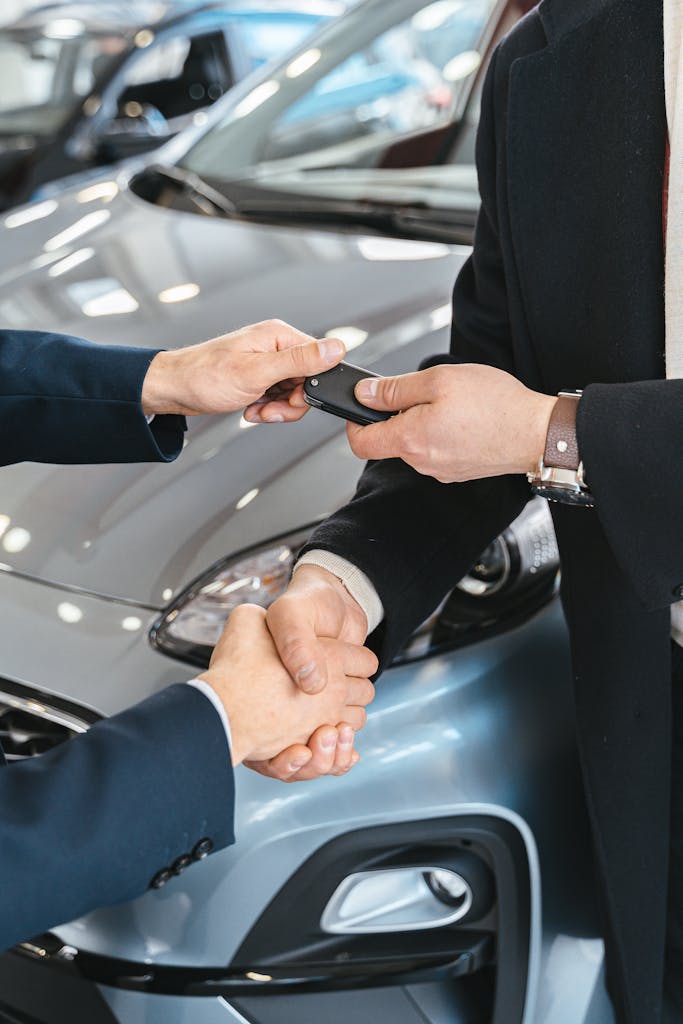 Imagen actual: Close-up of a business handshake as car keys are handed over, symbolizing a new car purchase.