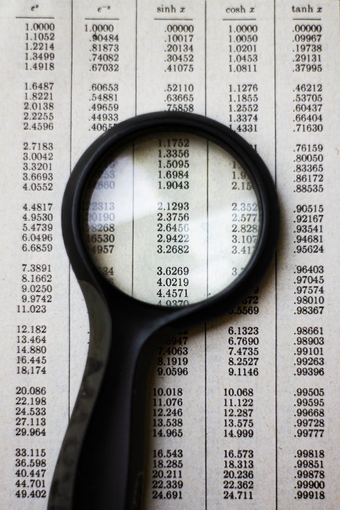 Imagen actual: A magnifying glass highlighting mathematical data on a page, emphasizing numbers and calculations.