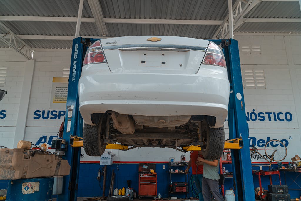 Imagen actual: A white Chevrolet car is lifted for maintenance in an automotive repair shop.